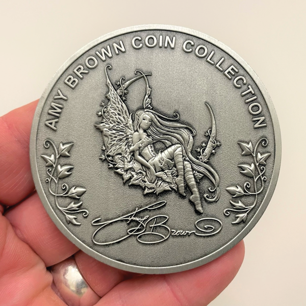 Load image into Gallery viewer, Silver metal coin in hand showing fairy, leaves, and words Amy Brown Coin Collection