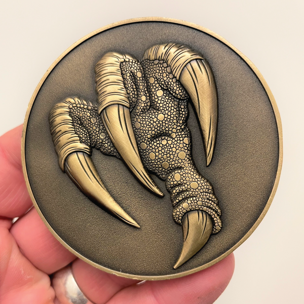 Load image into Gallery viewer, Gold metal coin in hand showing Griffon claws
