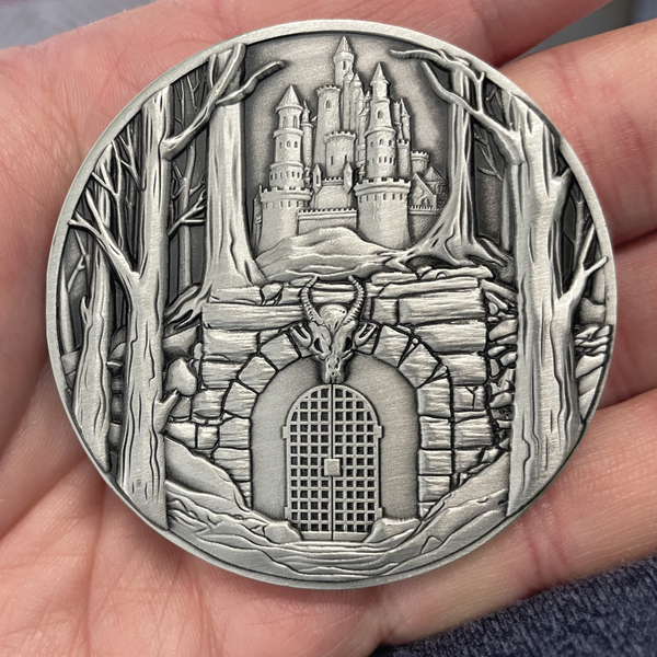 Load image into Gallery viewer, Silver painted coin in hand showing dungeon entrance below castle