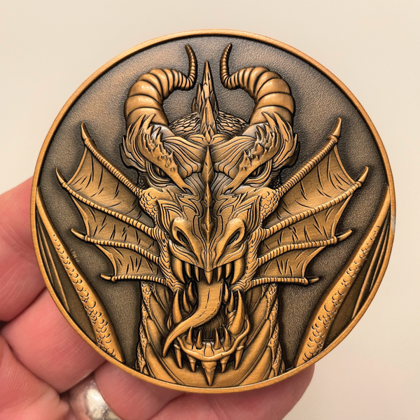 Load image into Gallery viewer, Copper metal coin in hand showing dragon head

