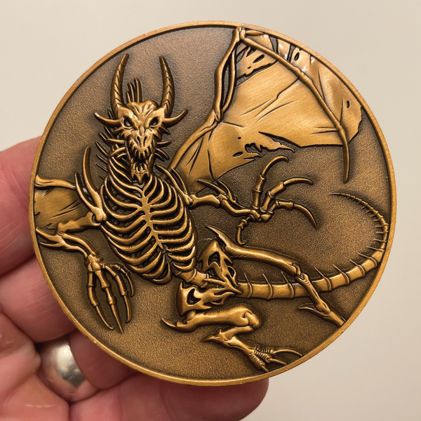 Load image into Gallery viewer, Copper metal coin in hand showing skeleton dragon
