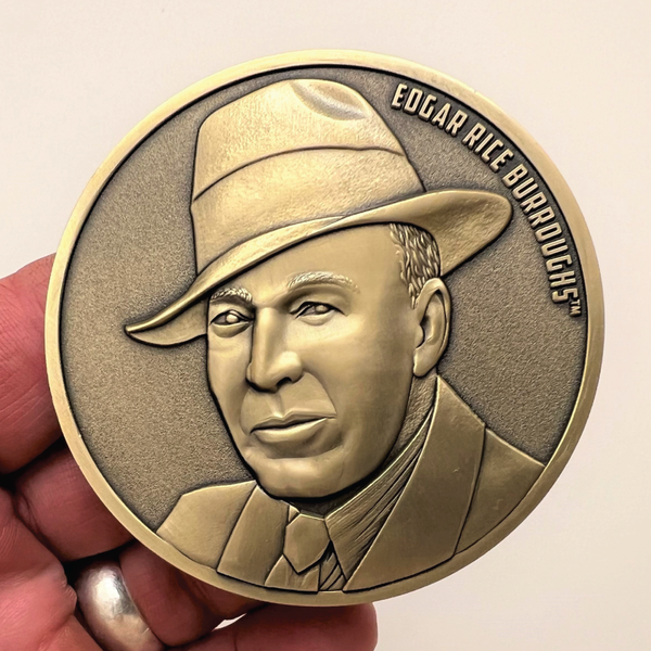 Load image into Gallery viewer, Gold metal coin in hand showing portrait of Edgar Rice Burroughs
