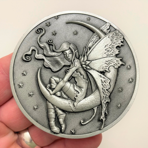 Load image into Gallery viewer, Silver metal coin in hand showing fairy sitting on moon
