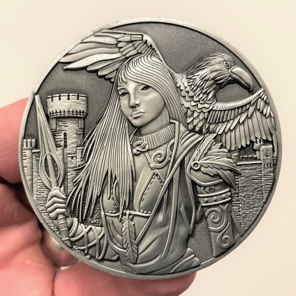 Load image into Gallery viewer, Silver metal coin in hand showing Morrigan