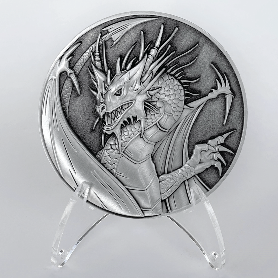 Silver coin on a plastic stand.  The silver coin has an image of a dragon