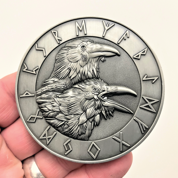 Load image into Gallery viewer, Silver metal coin in hand showing Ravens and runes
