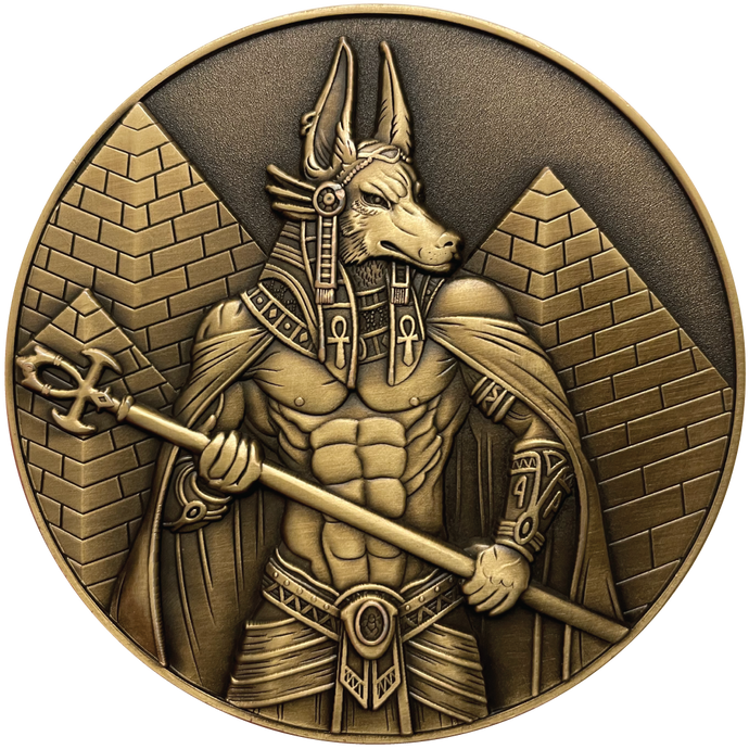 Gold metal coin showing Anubis next to pyramids
