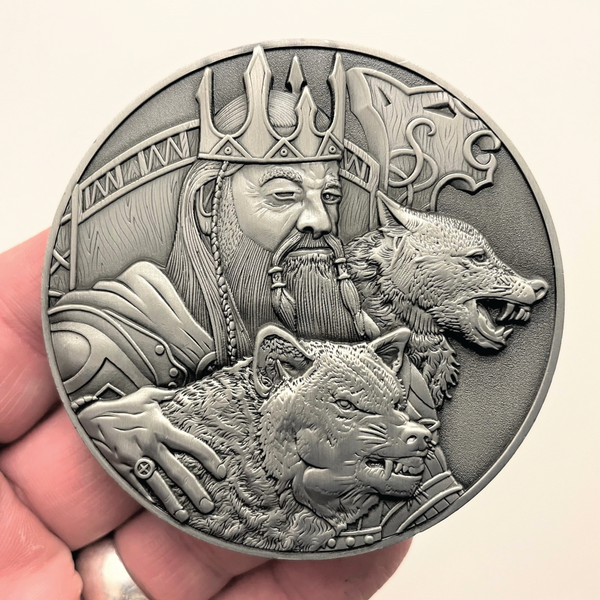 Load image into Gallery viewer, Silver metal coin in hand showing Odin and Wolves
