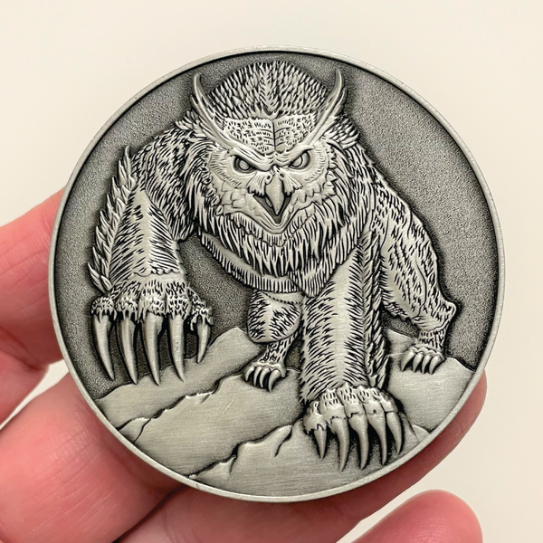 Load image into Gallery viewer, Silver metal coin in hand showing Owlbear
